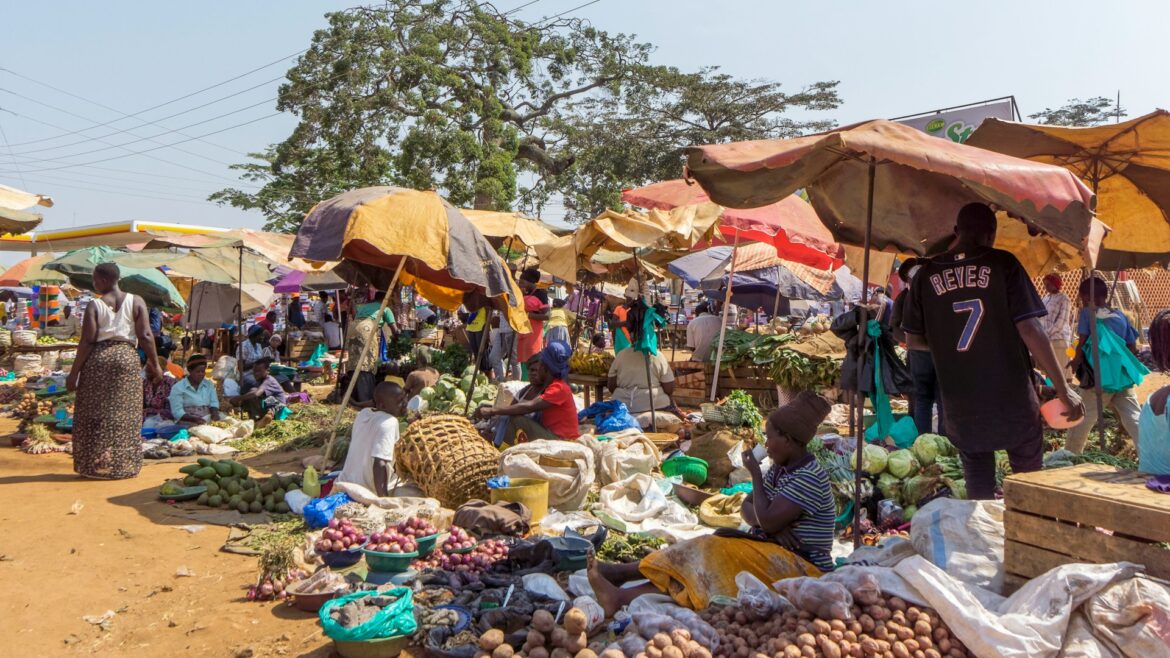 Vendors and buyers at a rural African market, exchanging a variety of fresh produce and goods